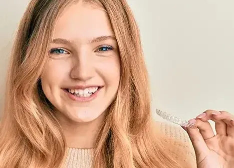 A patient holding a clear Invisalign aligner.